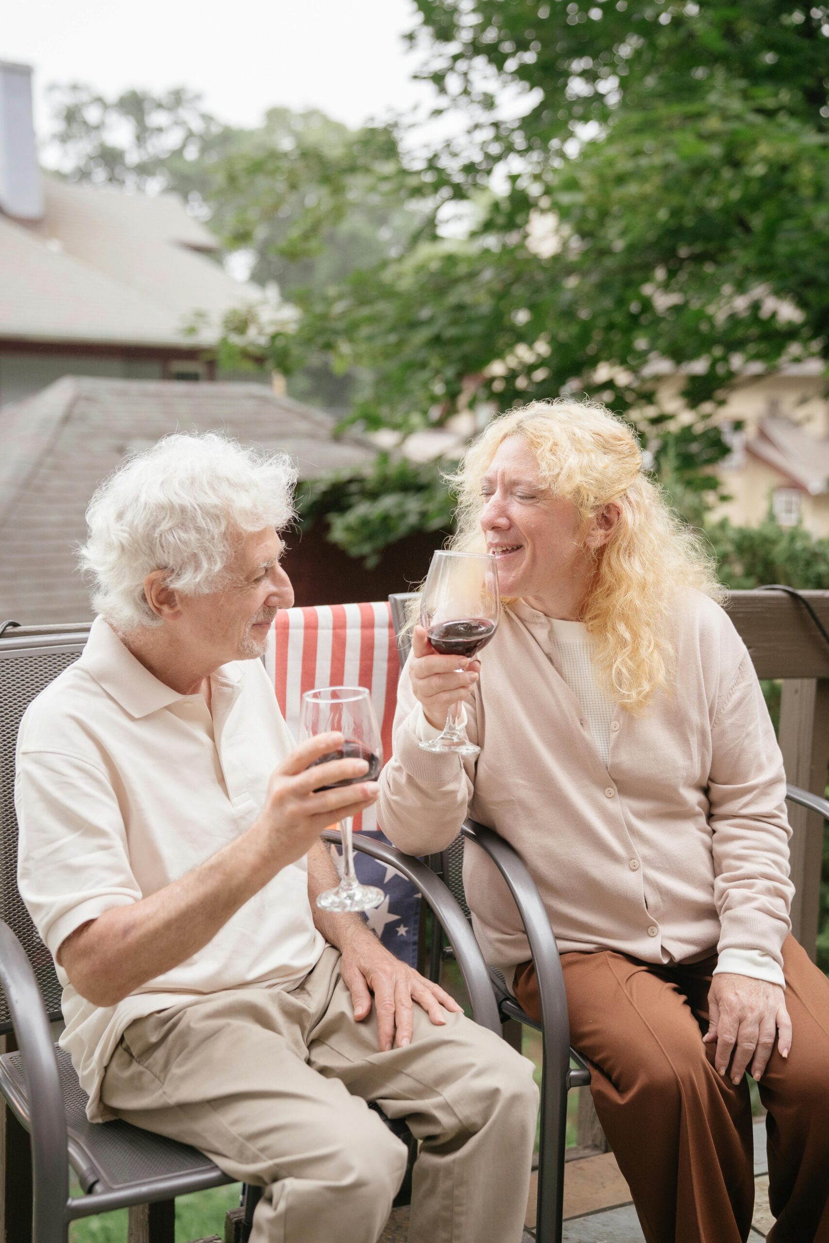 Smiling senior couple enjoying a wine toast outdoors, celebrating life together.